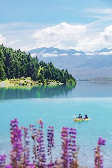 A coupld of asiasn riding the kayak in Tekapo lake on a sunny day with lupins in bloom