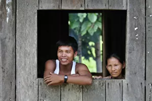 Images Dated 27th June 2012: Couple looking out of window in the Amacayon Indian Village, Amazon river, Puerto Narino