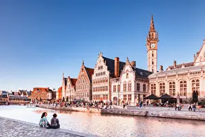 Gand Prints: A couple of persons sitting by the water canal with Ghent waterfront building at sunset