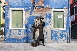 Couple in steampunk costumes in front of old blue house at Carnival time, Burano Island