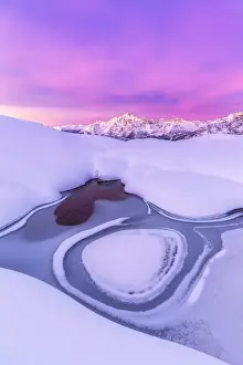 Cold Prints: Crazy shape in a frozen alpine lake at sunrise with view on Mount Disgrazia