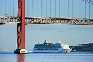 A cruise ship in the Tagus river, leaving the port of Lisbon, passes beneath the 25