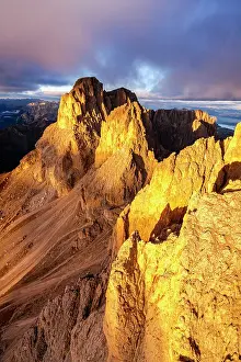 Climate Prints: Dramatic clouds over Sassolungo rock pinnacles lit by sunset in autumn