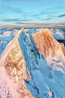 Tranquil Scene Collection: Dramatic sunrise over the steep rocks of the snowy Breidtinden mountain peak, aerial view