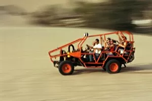 Adventurous Gallery: A dune buggy speeds tourists acoss through the sand