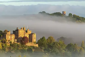 Dunster Castle and Conygar Tower emerging from morning mist, Dunster, Exmoor National Park, Somerset, England. Autumn (October) 2022