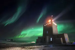 Aurora Boreale Prints: Dyrholaey lighthouse in winter with aurora borealis dancing above it, Sudurland, Iceland