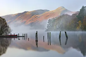 Early morning tranquil scenes of Derwent Water, with Catbells rising out of the mist in the background Early morning tranquil scenes of Derwent Water, with Catbells rising out of the mist in the background