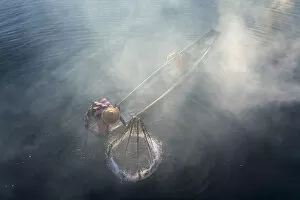Images Dated 23rd April 2020: Elevated view of fisherman catching fish from boat using traditional conical net at