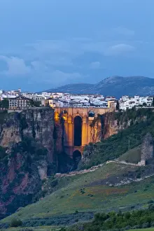 Night Time Prints: Elevated view over Puento Nuevo & the White Village of Ronda illuminated at dusk, Ronda