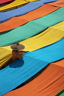Elevated view of woman hanging long pieces of dyed fabric to dry, Lake Inle