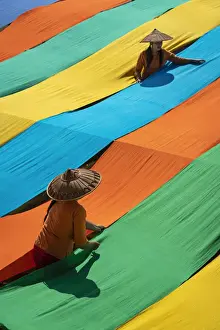 Two People Prints: Elevated view of two women hanging long pieces of dyed fabric to dry, Lake Inle