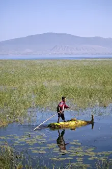 Sun Set Prints: Ethiopia, Lake Awassa. A young boy punts a traditional reed Tankwa through the reeds