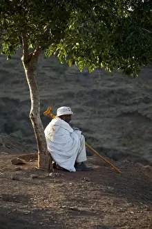 Ethiopia Prints: Ethiopia, Lalibela. An old man rests beneath a tree in the early morning light