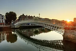 Europe, Dublin, Ireland, Tourists crossing Halfpenny bridge at sunrise