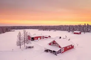 Isolated Prints: Europe, Finland, aerial view of a group of red buidlings on a frozen lake with the sun rising near Rovaniemi