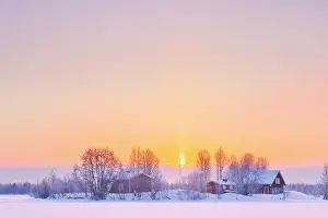 Sun Ray Prints: Europe, Finland, a group of traditional red buidlings on a little island in a frozen lake near Rovaniemi after a snow
