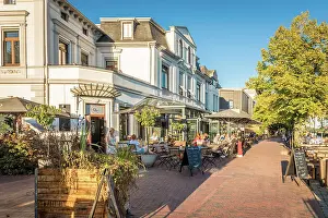 Summer Evening Prints: Evening atmosphere on the promenade with street cafes at the inland harbor of Oldenburg