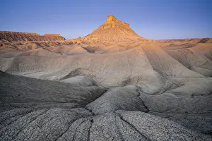 Factory Butte mountain rising above badlands at dawn, Wayne County, Utah Factory Butte mountain rising above badlands at dawn, Wayne County, Utah