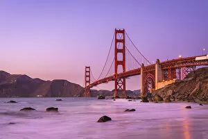 Golden Gate Bridge Collection: Famous Golden Gate Bridge over bay against purple sky during sunset, San Francisco