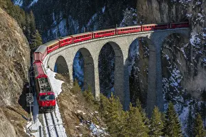 The famous red train of Albula mountain railway while passing on the Landwasser viaduct