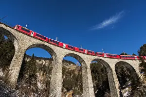The famous red train of Albula mountain railway while passing on the Landwasser viaduct