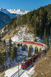The famous red train of Albula mountain railway passing through a scenic winter alpine