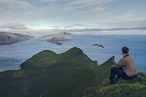 Images Dated 6th October 2021: Faroese guy sitting along Knukur mountain in Mykines. Faroe Islands