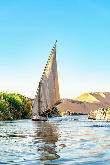 Dune Prints: A felucca sails on the Nile River near the Aswan cataracts, Egypt