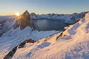 First lights of sunrise on Mount Segla and Mefjorden framed by the frozen sea seen