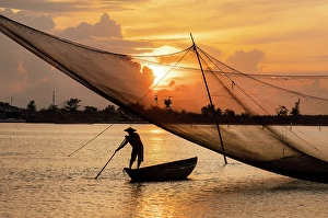 Fisherman checking his net at sunrise, Cua Dai fishing village, near Hoi An, Central Vietnam
