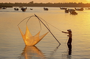 Vietnamese Prints: Fisherman lifting his traditional net from the water at sunrise