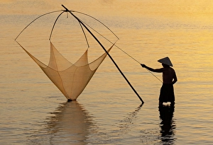 Hoi An Prints: Fisherman lifting his traditional net from the water at sunrise