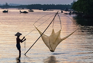 Hoi An Prints: Fisherman lifting his traditional net from the water at sunrise