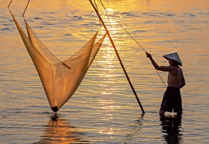 Hoi An Prints: Fisherman lifting his traditional net from the water at sunrise