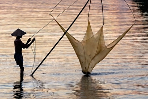 Hoi An Prints: Fisherman lifting his traditional net from the water at sunrise