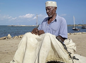 Islamic Dress Gallery: A fisherman repairs the sail of his wooden sailing boat