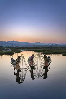 Males Collection: Three fishermen holding typical conical nets on their boats before sunrise