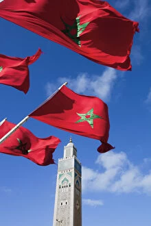 Flags of Morocco waving in the wind and Hassan II Mosque, the third largest mosque