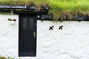 Flowerpot and ornaments on facade of iconic house with grass roof, Mykines island