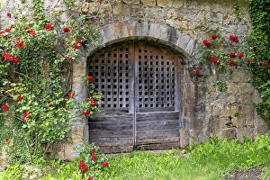 Images Dated 5th June 2023: France, Occitanie, Lot, an old door surrounded by roses at the chateau de Montal