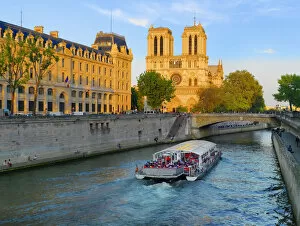 Images Dated 27th July 2011: France, Paris, Notre Dame Cathedral and tourist boat on River Seine at sunset