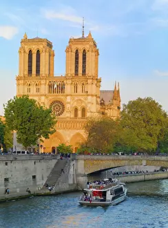 France, Paris, Notre Dame Cathedral and tourist boat on River Seine at sunset