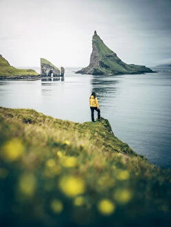 Girl admiring Drangarnir and Tindholmur Faroe Islands, Europe
