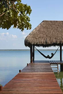 Images Dated 7th June 2022: Girl with hat in a hammock looking at Bacalar lagoon from a pier, Quintana Roo, Yucatan, Mexico