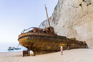 A girl in a hat looking at the shipwreck on Navagio Beach or Shipwreck Beach, Zakynthos, Zante, Ionian Islands, Greece