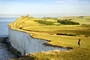 Early Morning Prints: Girl looking at the Seven Sisters Cliffs in the early morning with Belle Tout lighthouse