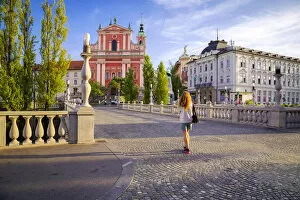 A girl walking in the old town of Ljubljana, with the Triple Bridge and the iconic