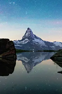 Zermatt Prints: Glowing stars reflecting in lake Stellisee with majestic Matterhorn on background at night