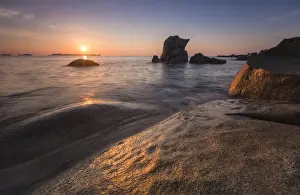 The golden lights of sunrise are reflected on the blue sea and cliffs Punta Molentis